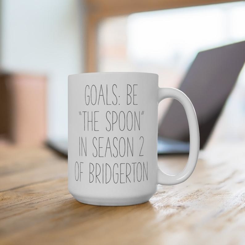 a white mug with thin black writing that says &quot;goals: be the spoon in season 2 of bridgerton&quot; on it