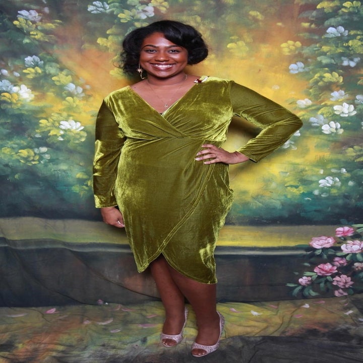 Reviewer wears green velvet long-sleeve wrap dress with pink peep-toe heels
