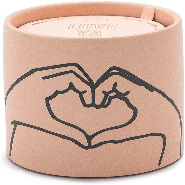 a dusty pink candle with two hands forming a heart on it