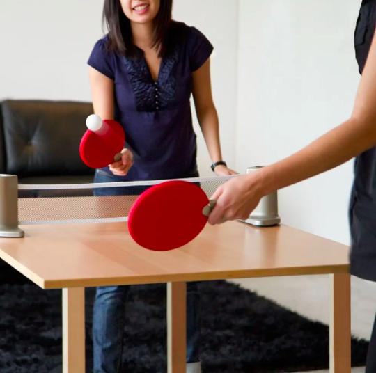 Two people playing ping pong on a dining table