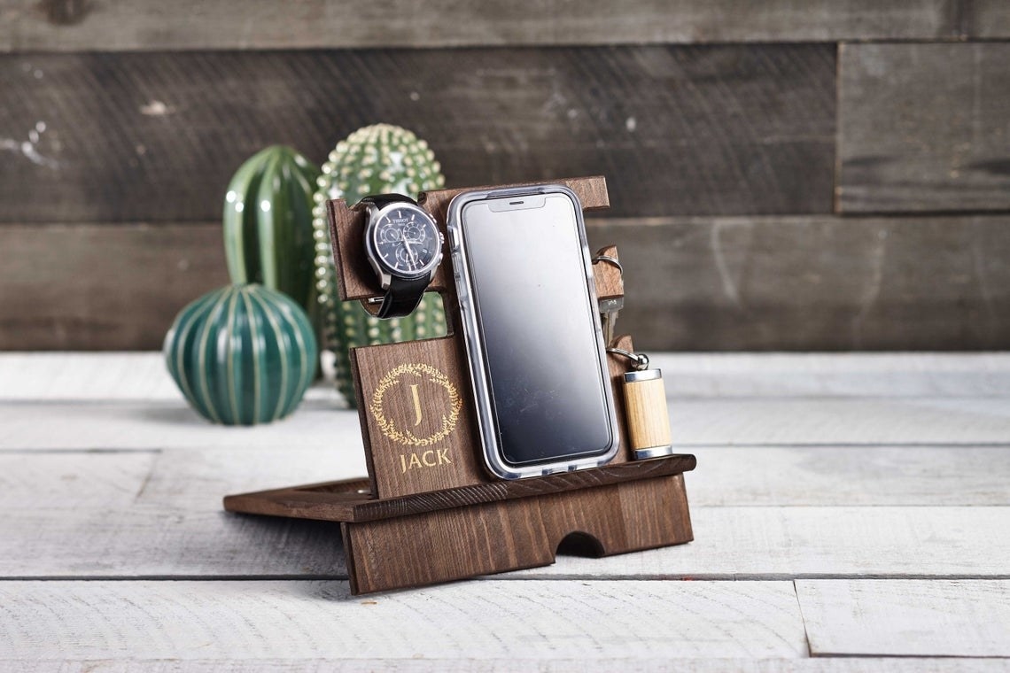 A wooden desk caddy with a phone, watch and keys on it 