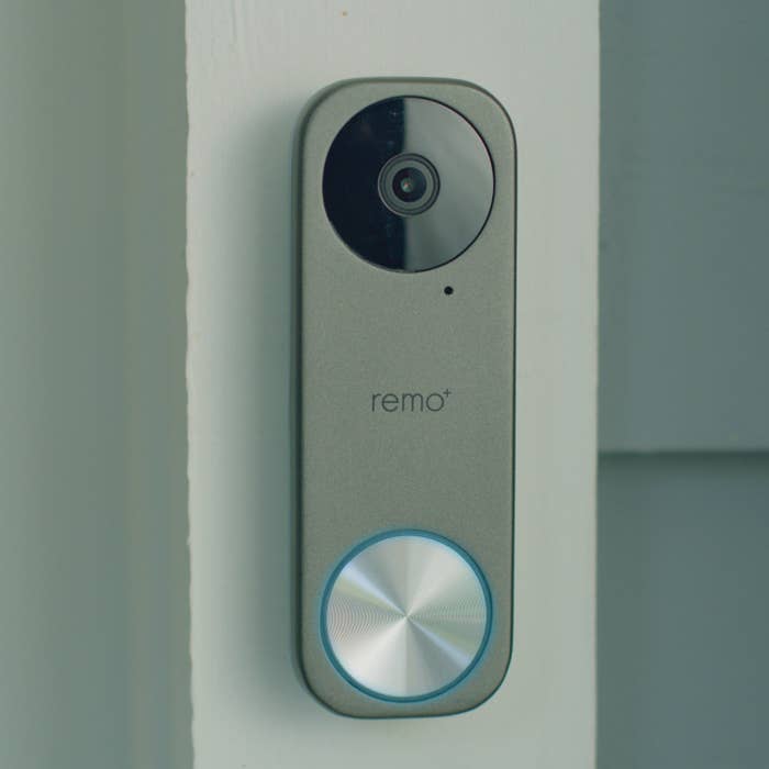 The doorbell with a circular button and camera outside of a front door