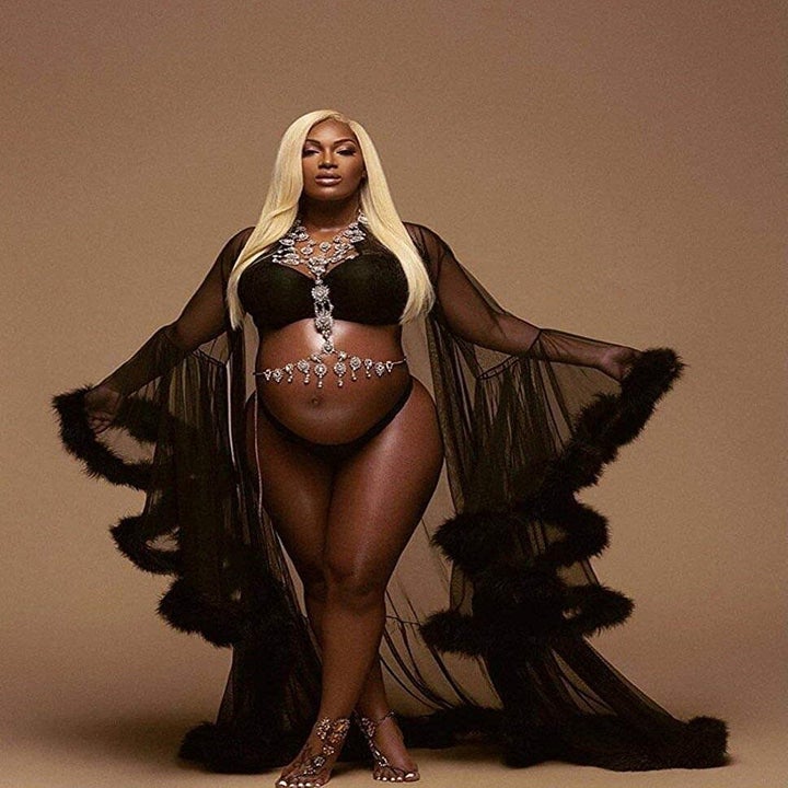 Model wearing sheer black robe with ruffed fluffy edges. It cascades in twists at the wrists down to the floor-length bottom.