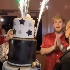 Jake claps while a giant cake is brought to him