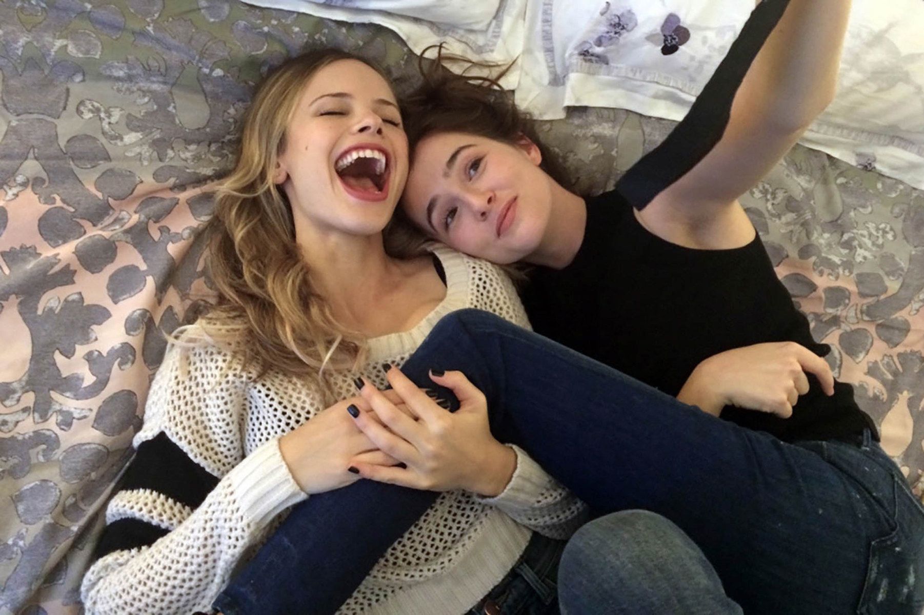 Lindsay and Samantha lying in bed together smiling