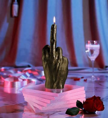Hand shaped candle with flame starting at upturned middle finger 