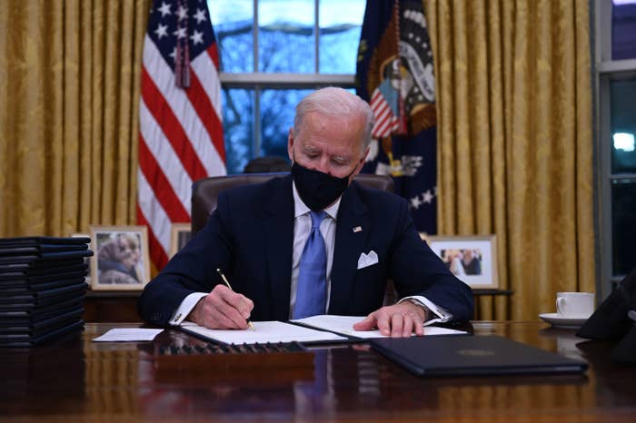 Joe Biden signing a document in the Oval Office
