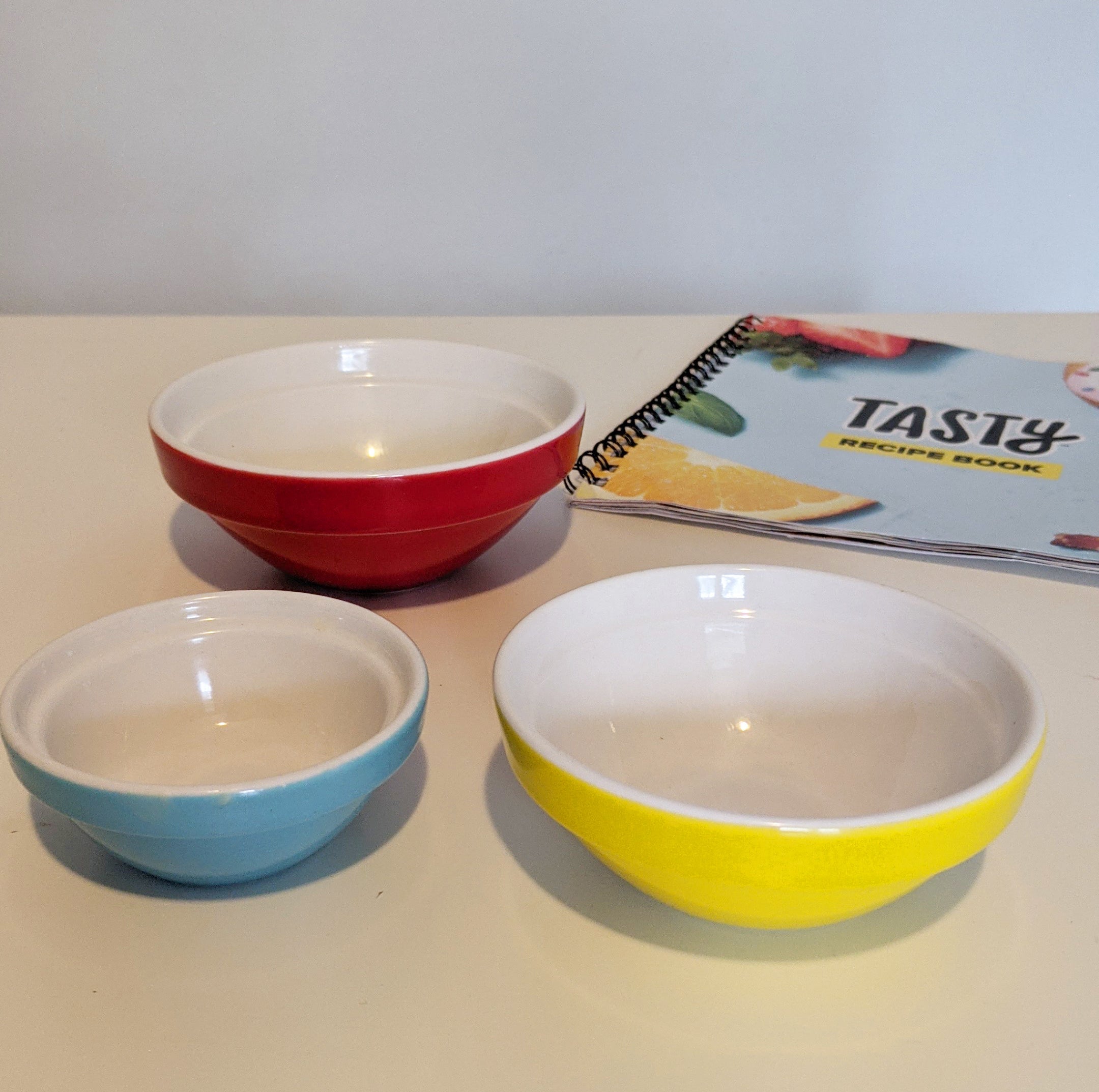 Three pinch bowls of different sizes on a table with a recipe book