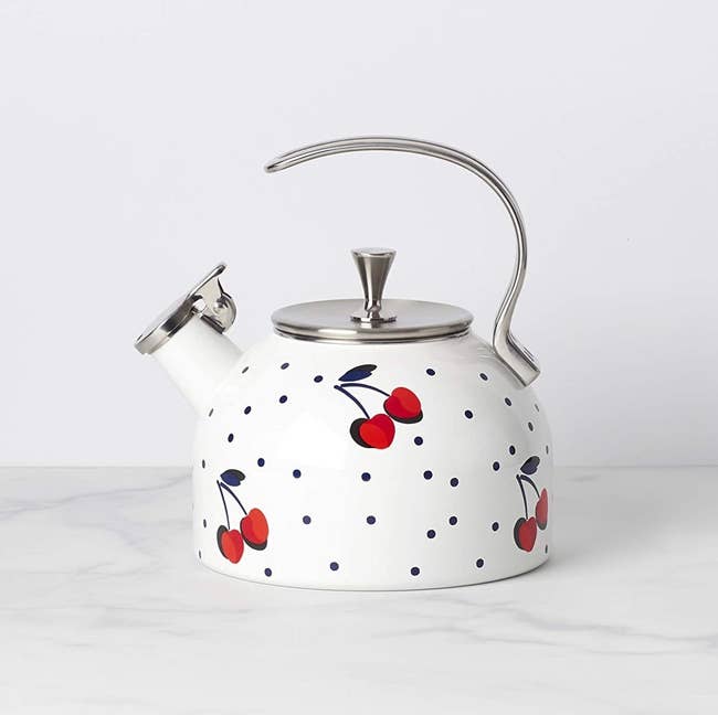 The polka-dotted white kettle which has a cherry pattern