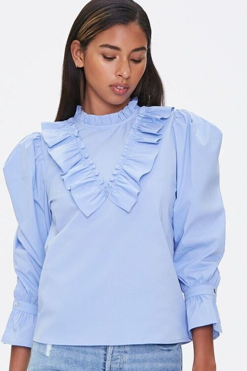 Model wearing the blue three-quarter sleeve top with a mock neck, puff sleeves, and ruffles