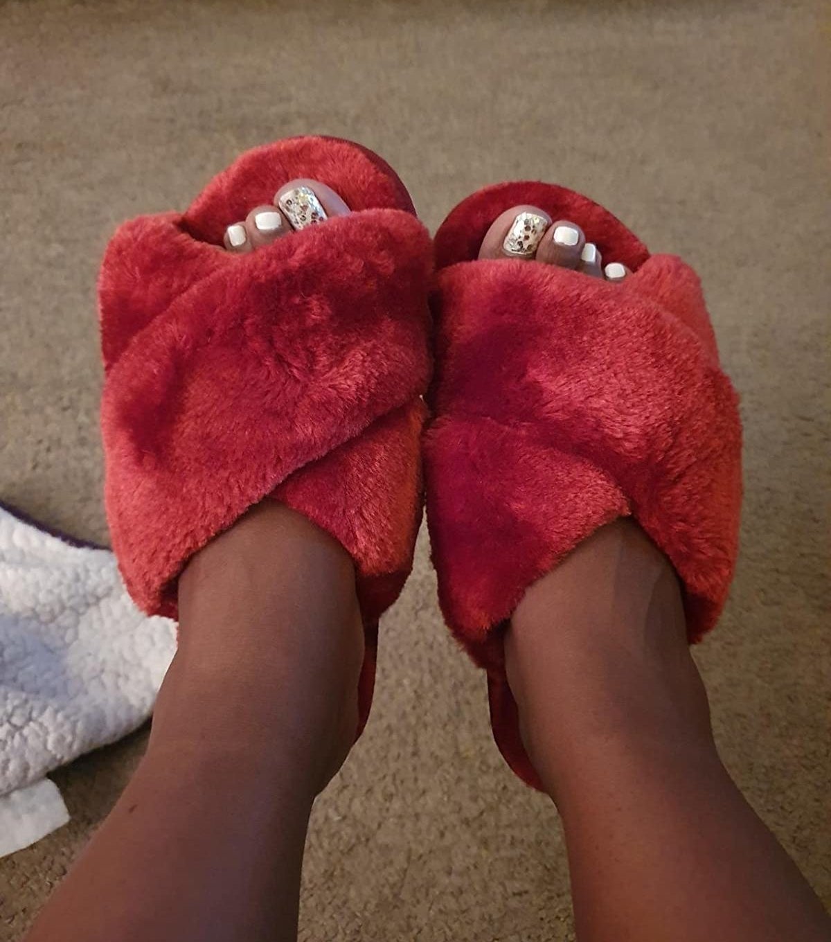 reviewer image of a customer&#x27;s feet in the red fluffy slippers