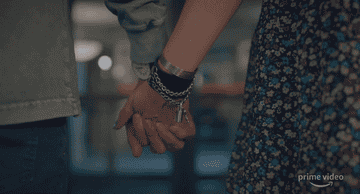 The pair hold hands. 