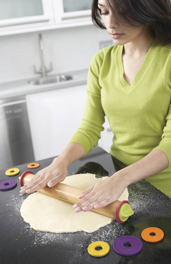 person using an adjustable rolling pin to roll out dough
