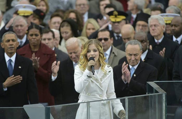 Jackie is wearing a bedazzled coat as she sings the anthem