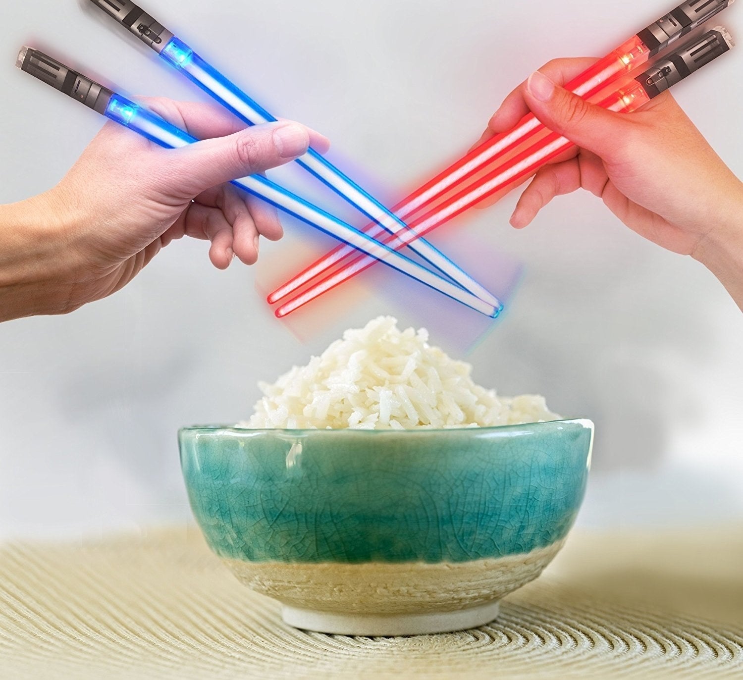 Two handles holding a pair of blue and red chopsticks that look like lightsabers over a bowl of rice