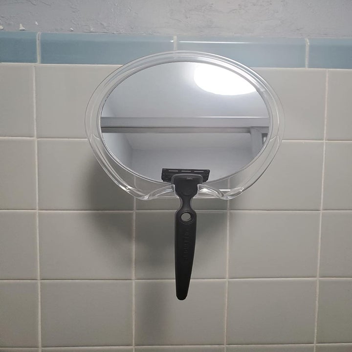 The mirror suctioned to the wall and holding a razor