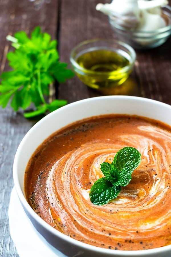A bowl of creamy tomato soup with herbs.