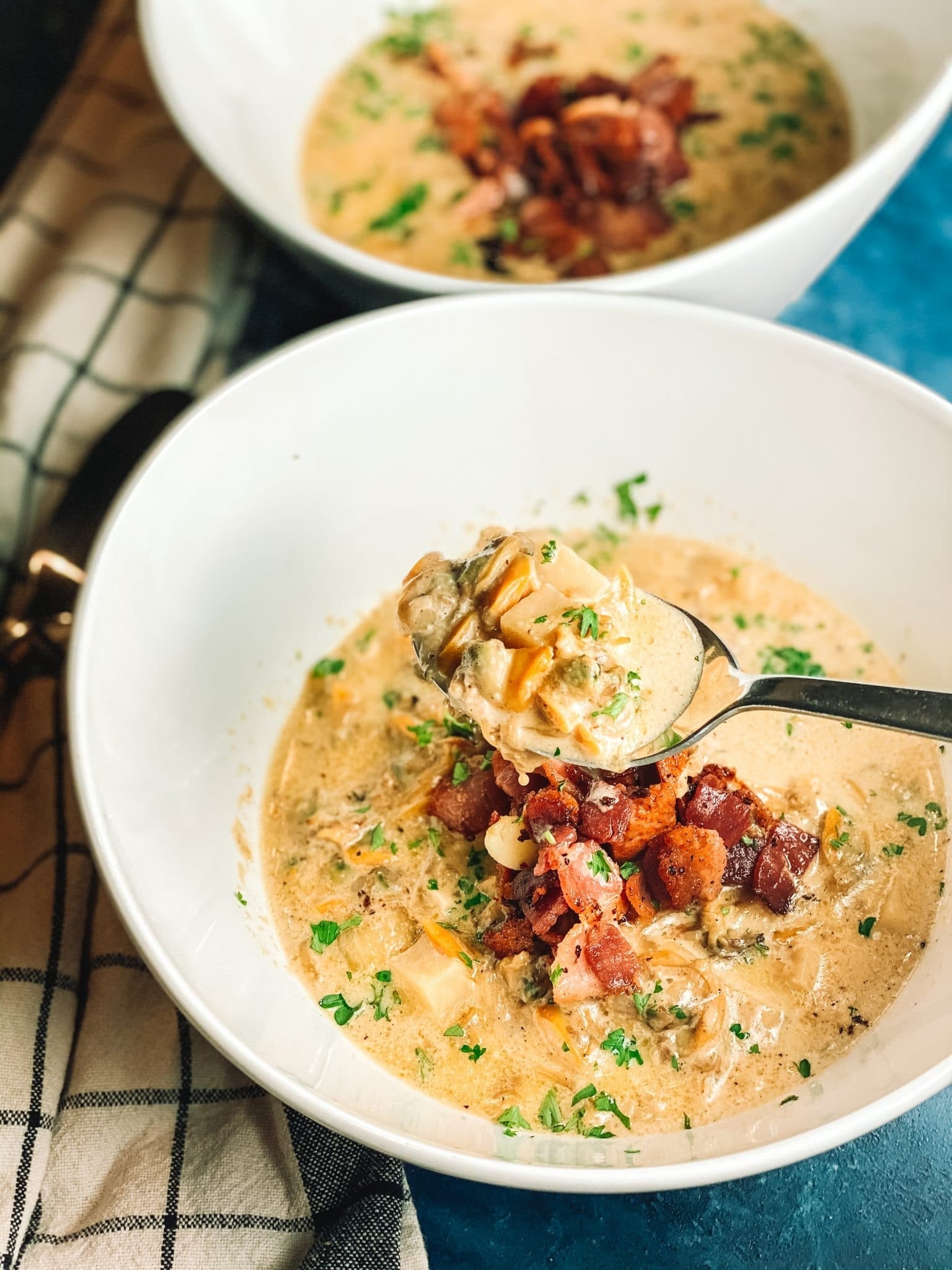 Two bowls of thick New England clam chowder with bacon.