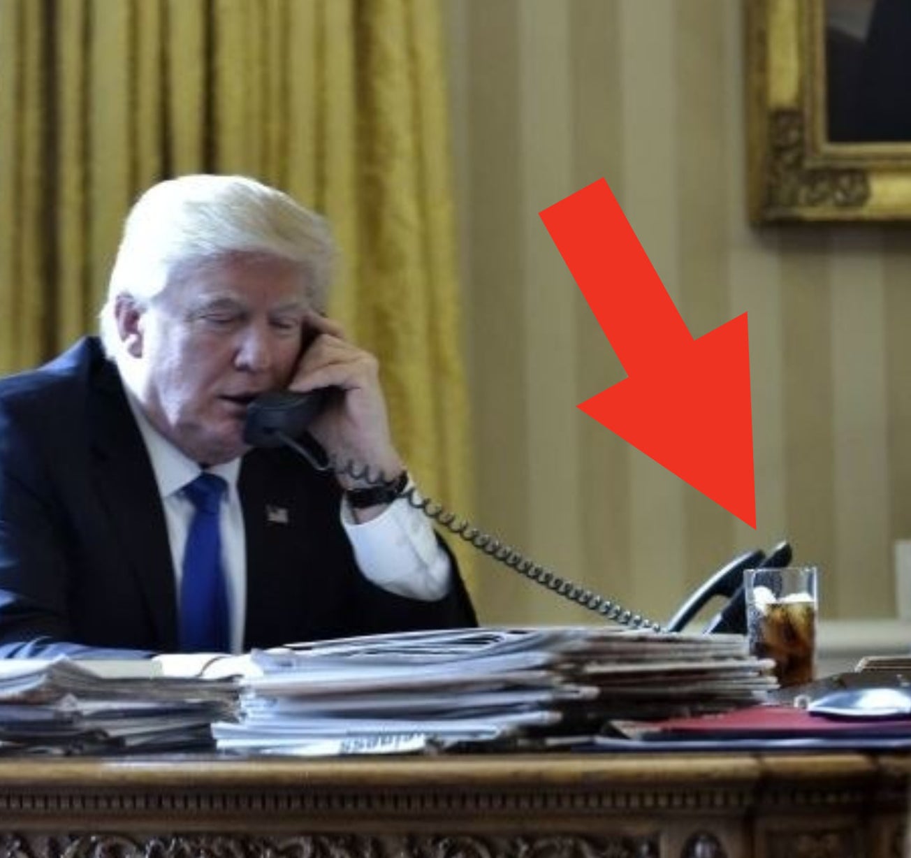 Trump on the phone with a tall glass of Diet Coke on his desk next to stacks of papers