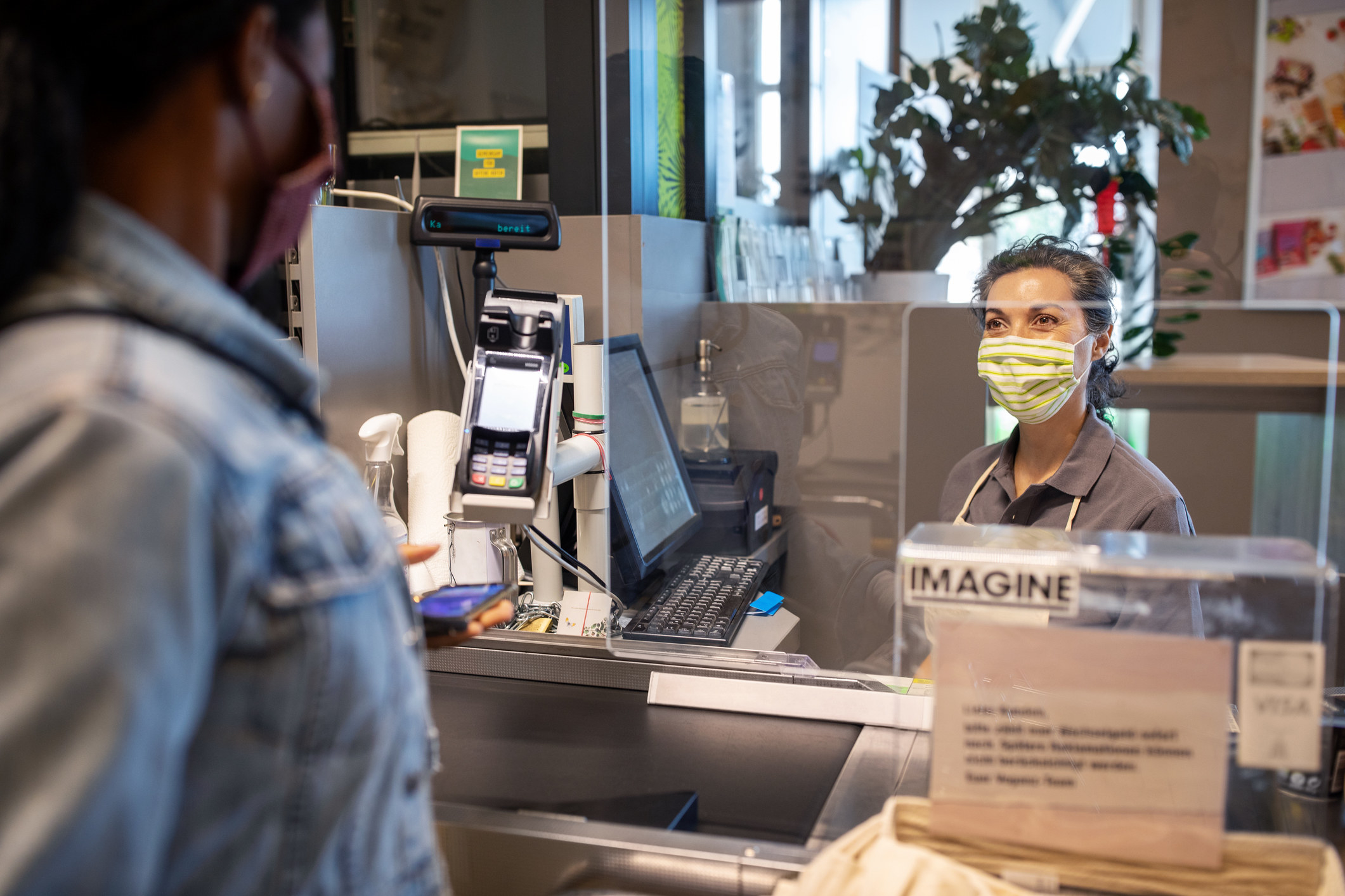 a person at the checkout, where there is a protective shield