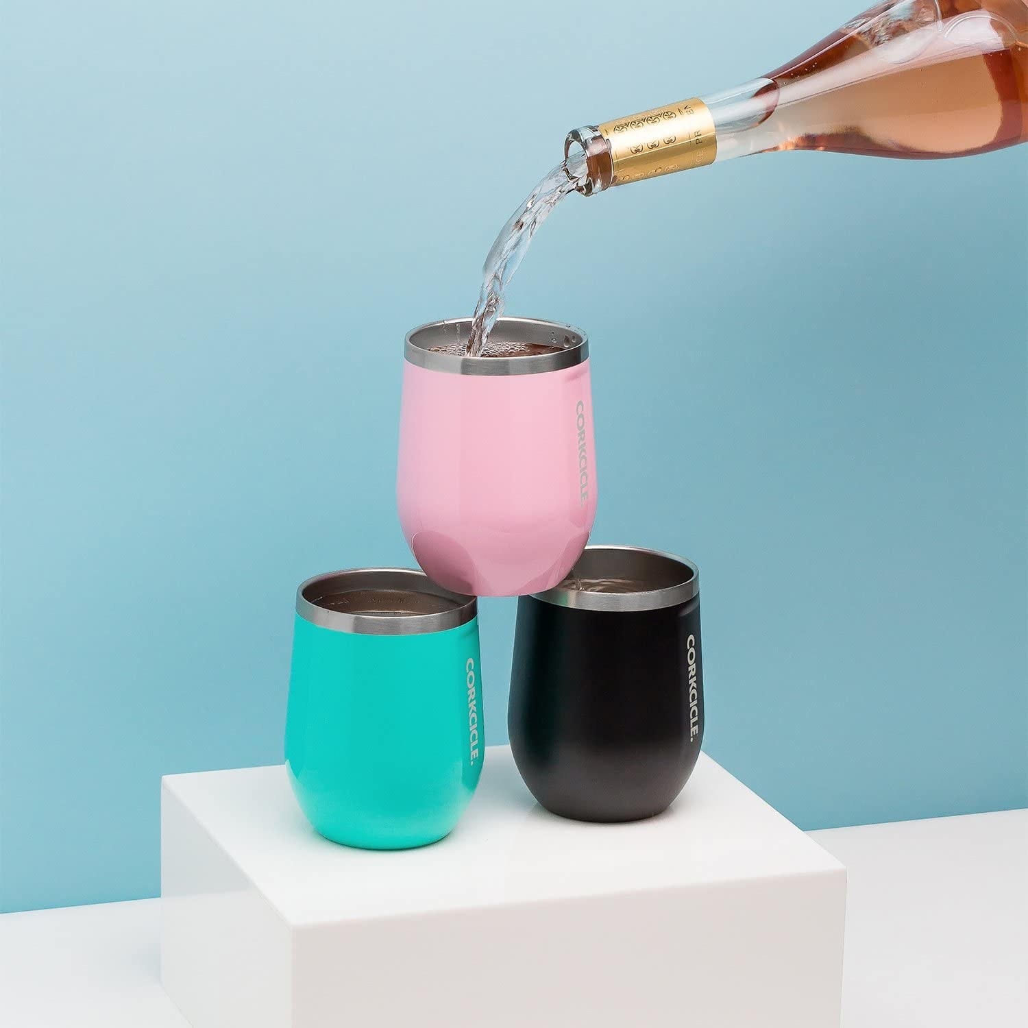 three different colored corksicle tumblers stacked, with wine being poured into one