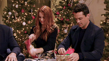 A group of people excitedly open gifts
