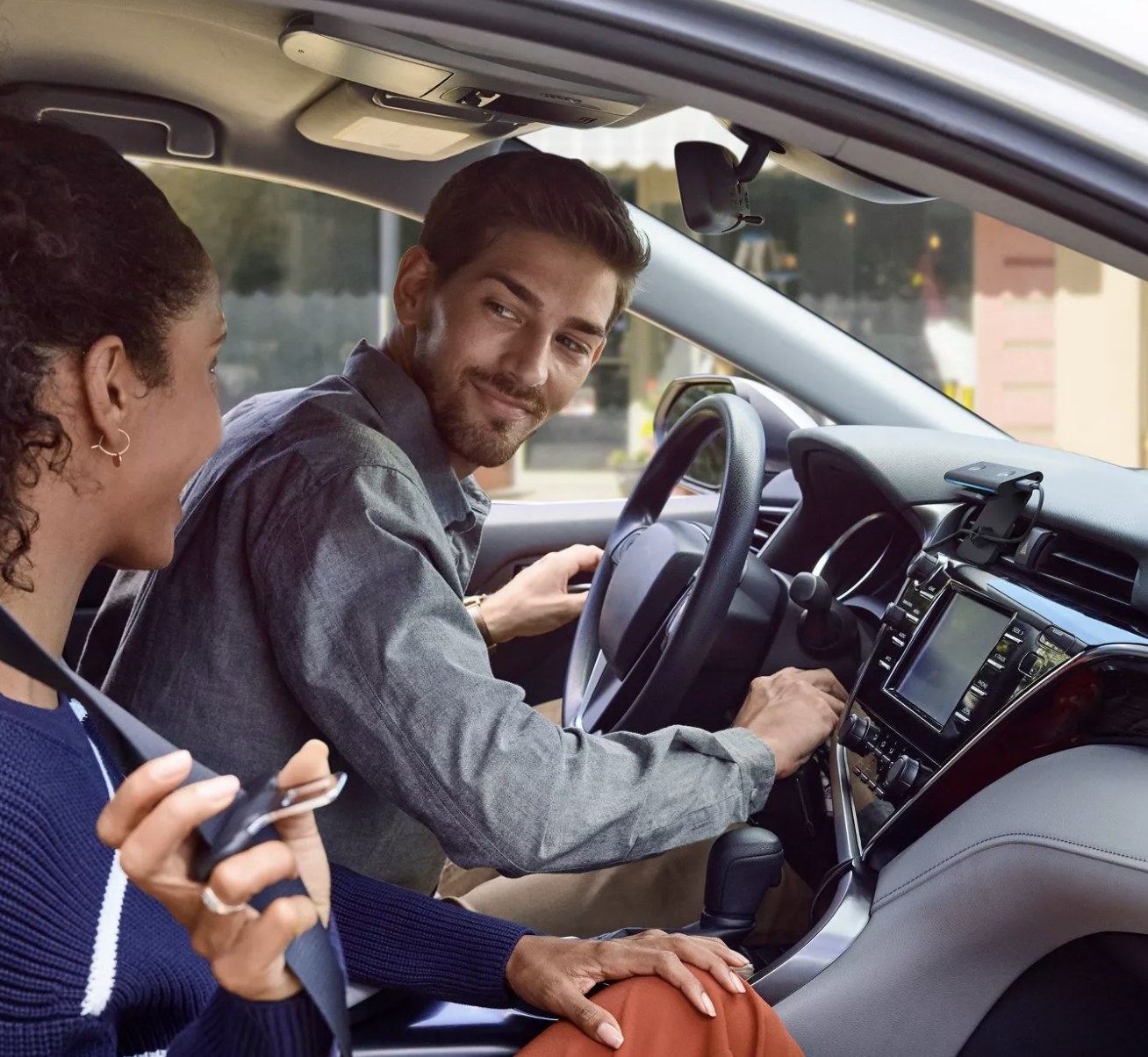 Two people in a car with an Amazon Echo Auto clipped to the car vents
