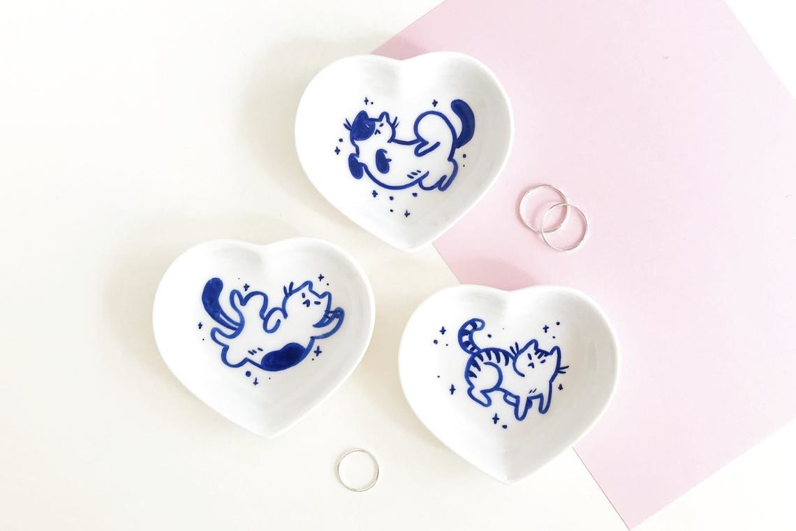 three heart shaped dishes with a blue illustrated cat on each