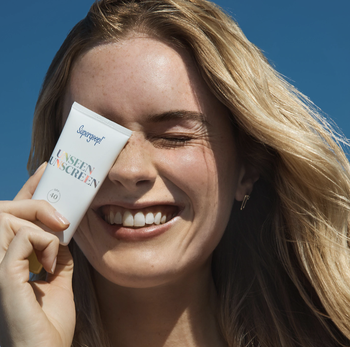 Model holding jar of Supergood Unseen Sunscreen