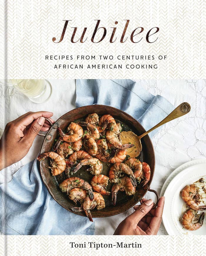 The cover of the cookbook which shows a person holding a pan of shrimp
