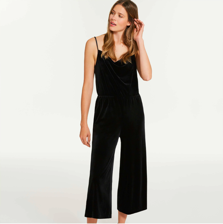A person wearing soft velvet jumpsuit with thin spaghetti straps and flowy cropped pants