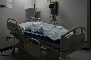 A deceased patient in a body bag on a bed in a COVID-19 intensive care unit.