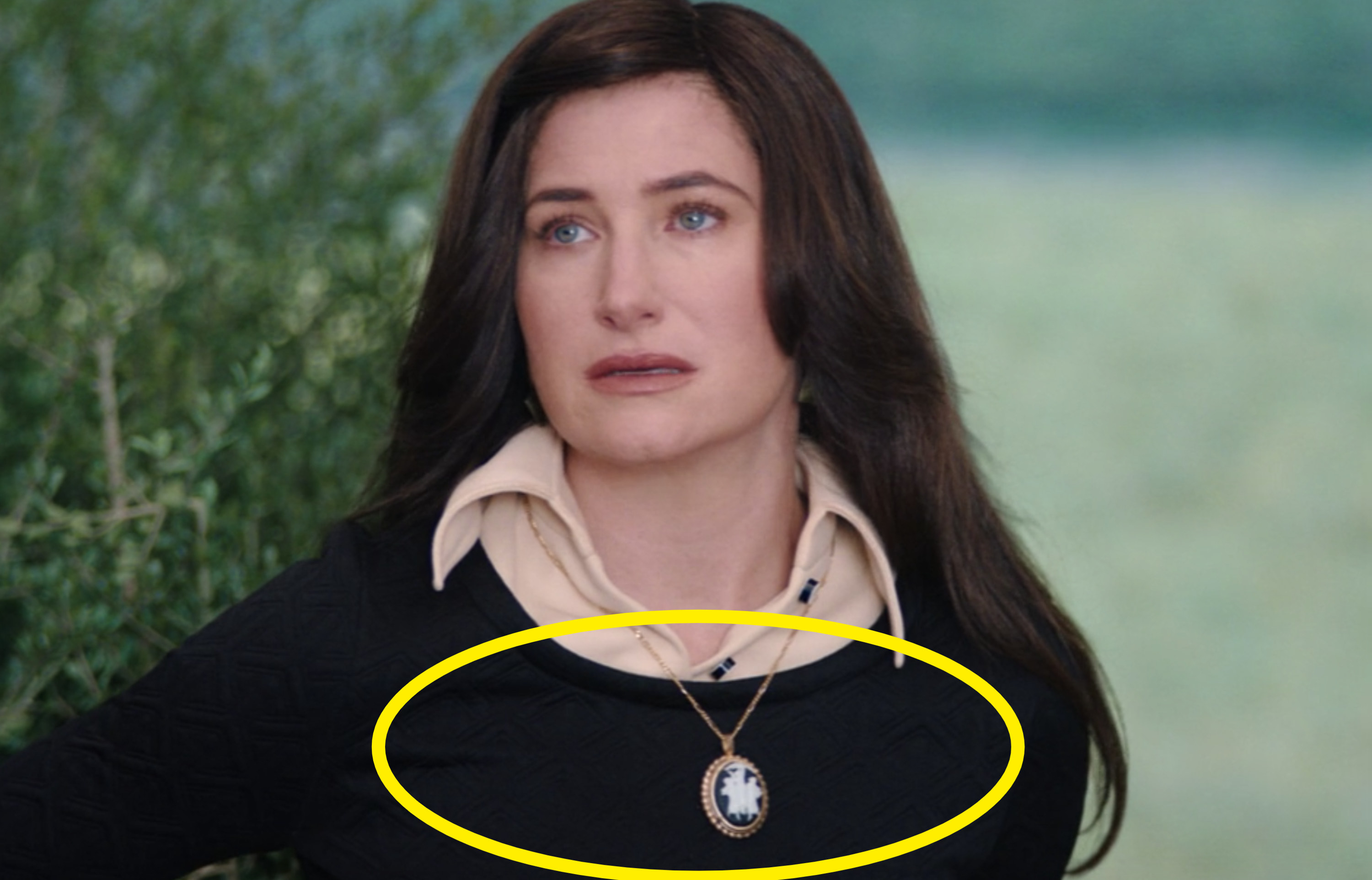 Agnes wearing a black sweater with a large broach on a necklace