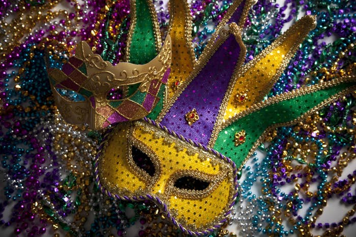 Two Mardi Gras masks on top of a pile of beads