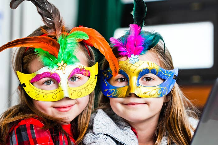 Two little girls wearing colorful Mardi Gras masquerade masks