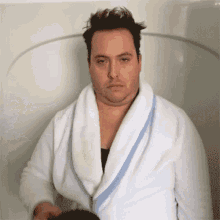  A GIF of a man in a dressing gown poring a large cup of black coffee on himself.