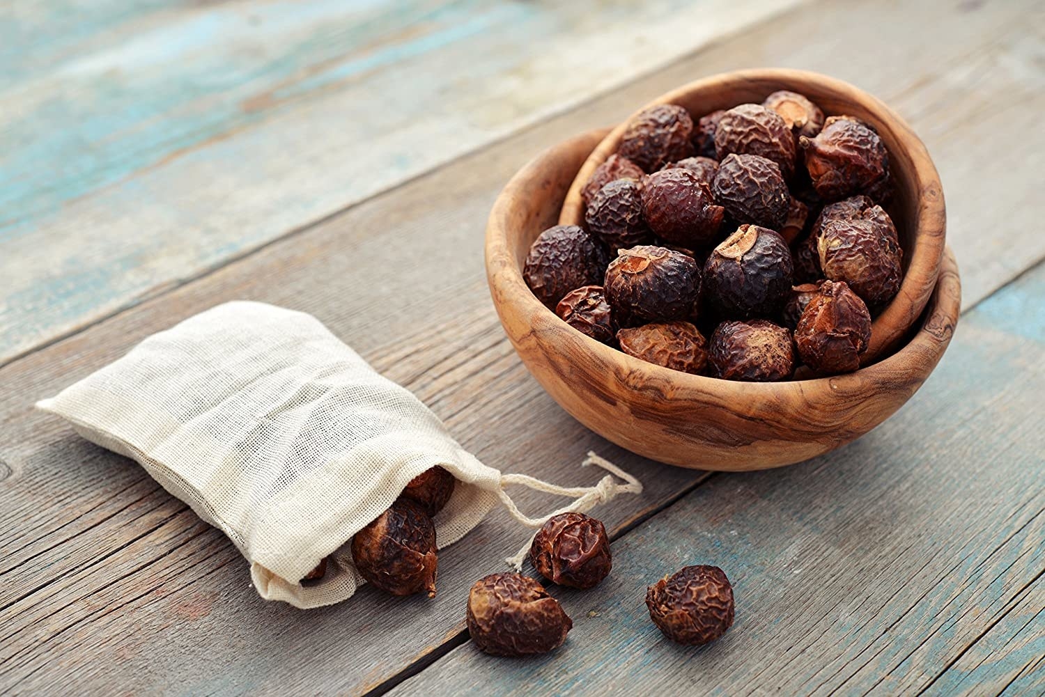 a bag and a bowl of the soap nuts on a wooden table 