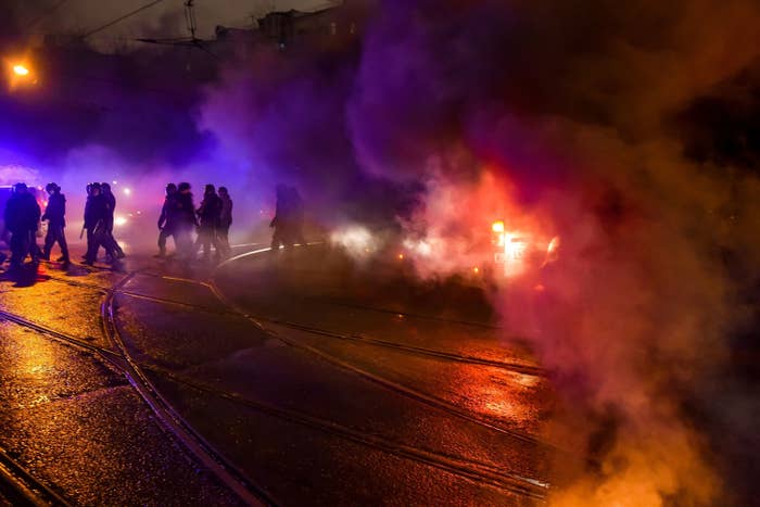 Policemen walk in the smoke from a burning flare thrown by protesters not far from where opposition leader Alexei Navalny is being held.