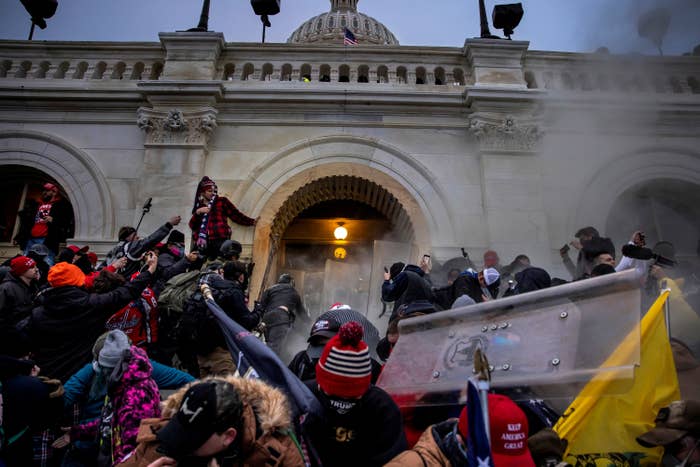 A group of people, some wearing Trump regalia, clash with police on the steps of the Capitol building
