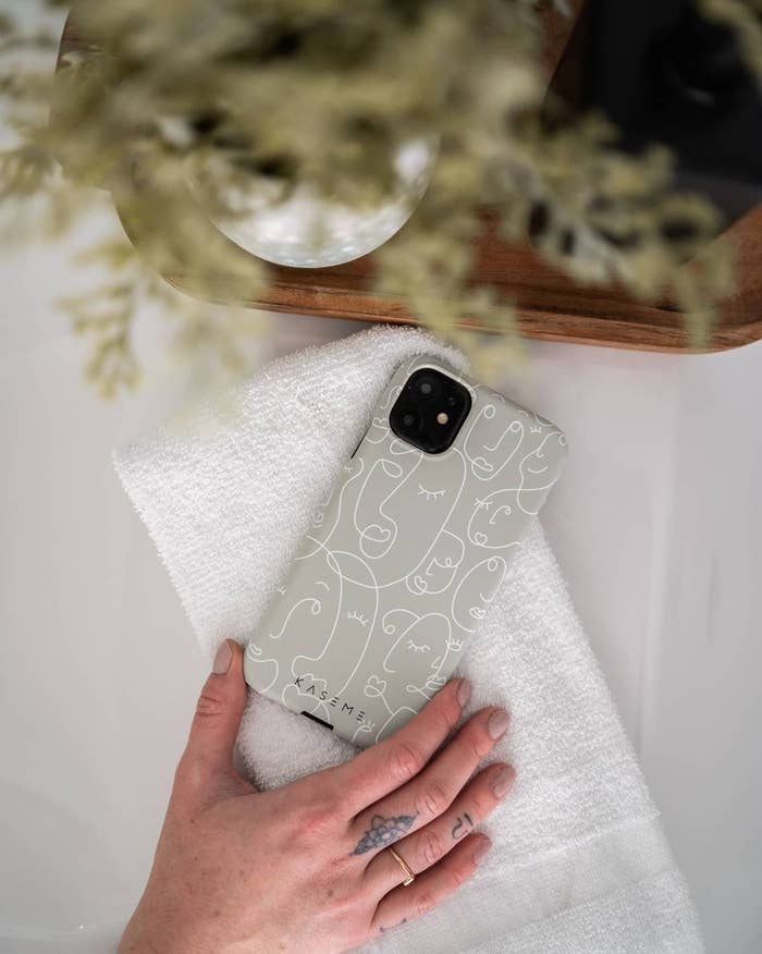 An iPhone on a table with a hard case that has an illustrated face print on it