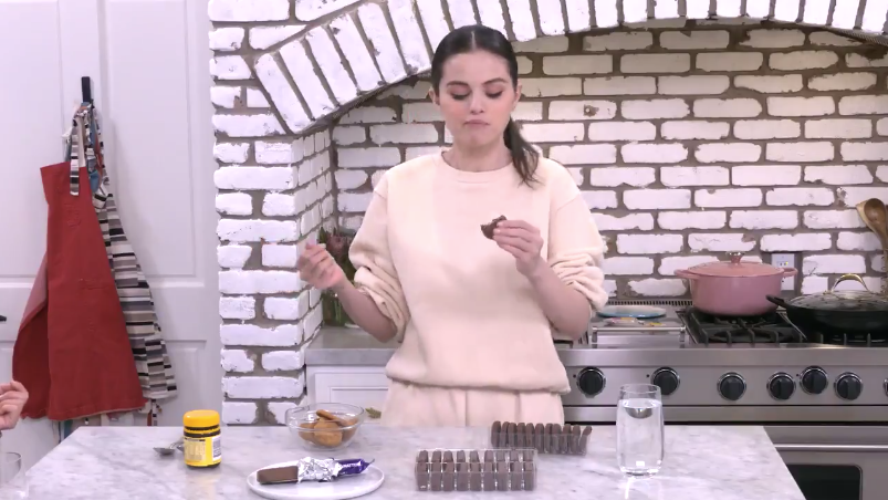 Selena in her kitchen, holding up a Mint Slice which has a bite taken out of it