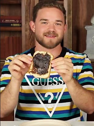 A man holding a piece of bread slathered with Vegemite