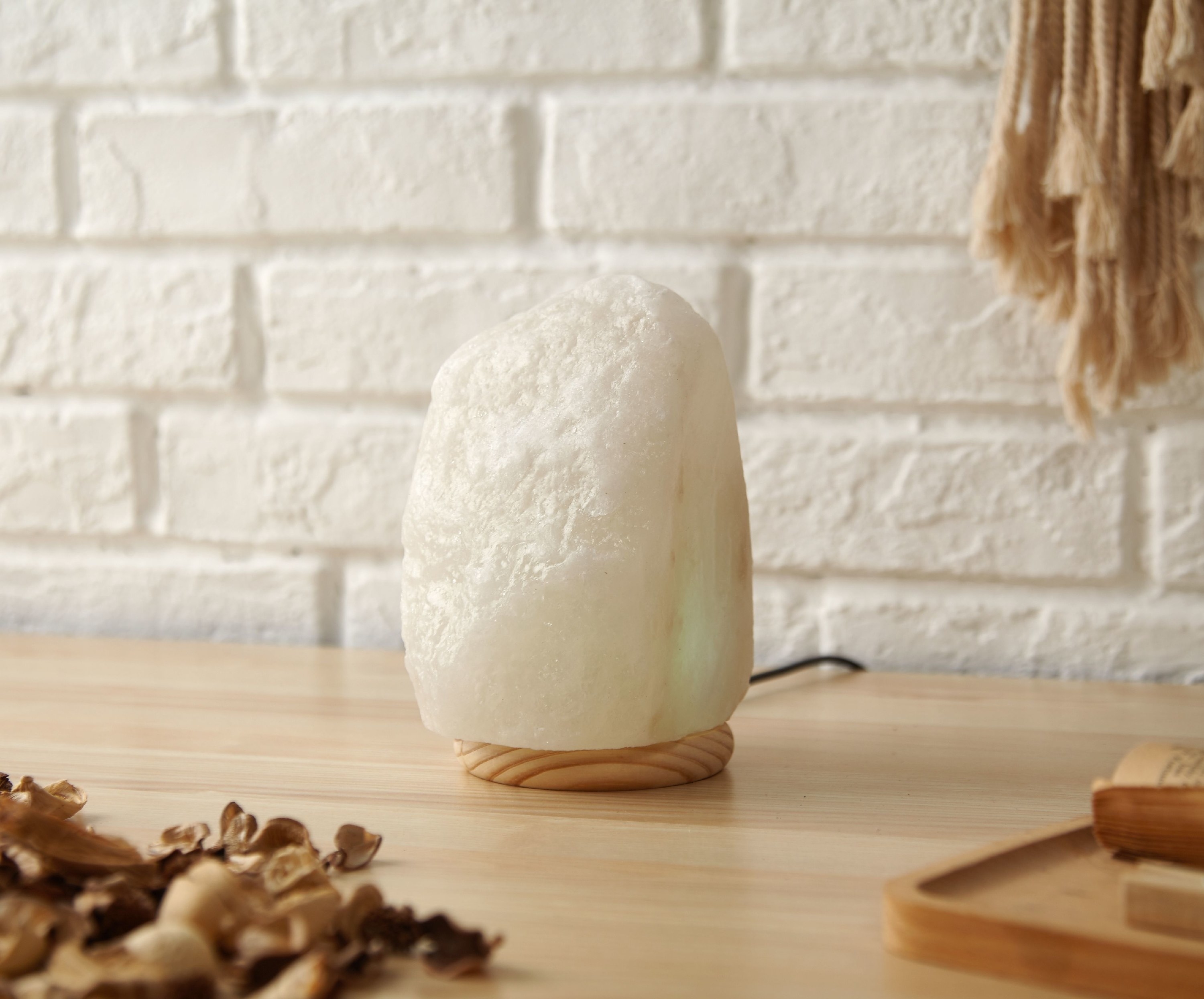 A white salt lamp with a wooden base on a table