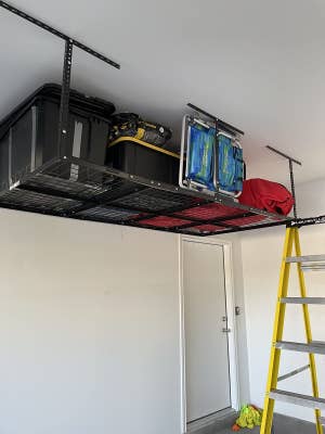 A different reviewer's photo of their black shelving unit with various chairs and storage bins