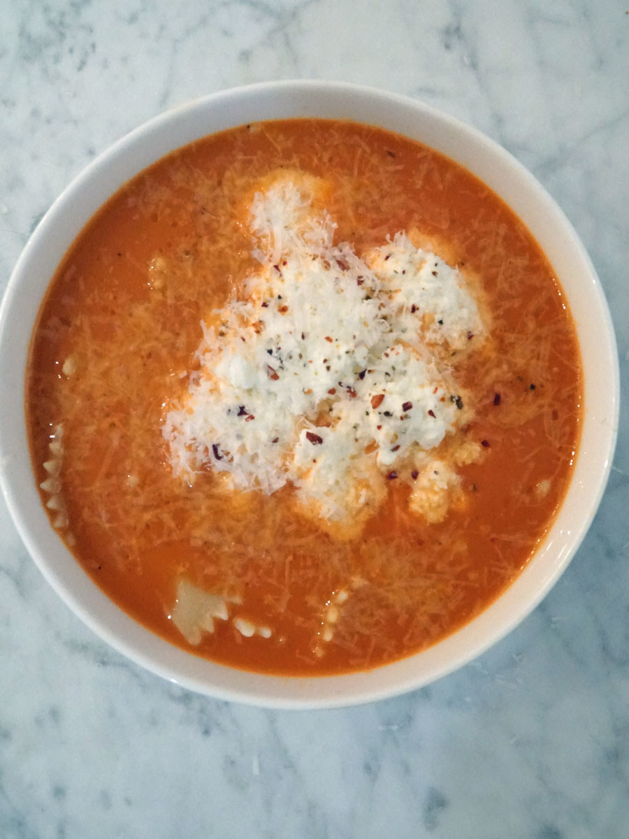A bowl of lasagna soup with ricotta and bowtie noodles.