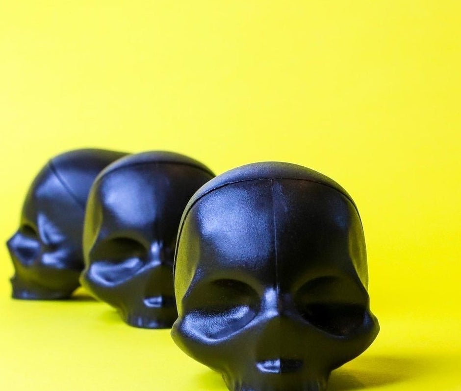 A trio of skull-shaped lip balms on a bright background