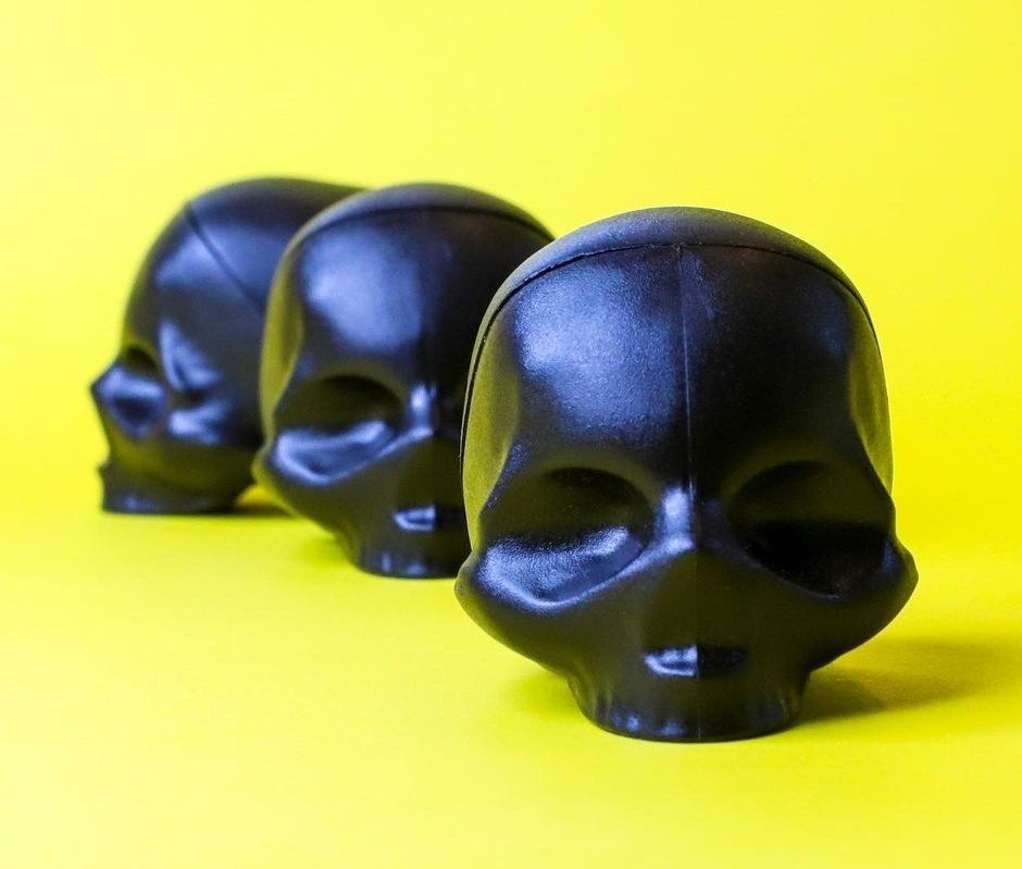 A trio of skull-shaped lip balms on a bright background