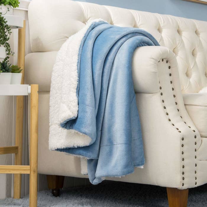 A blue faux fur blanket draped on a beige couch.