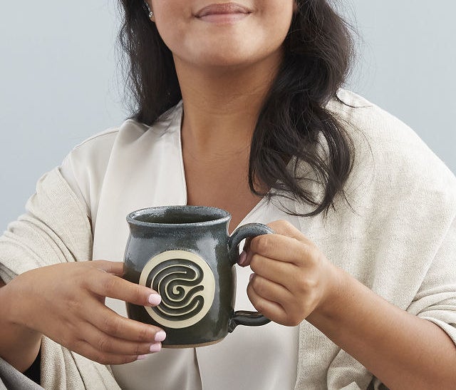 A model holding the meditation mug and tracing their finger on the grooved design 