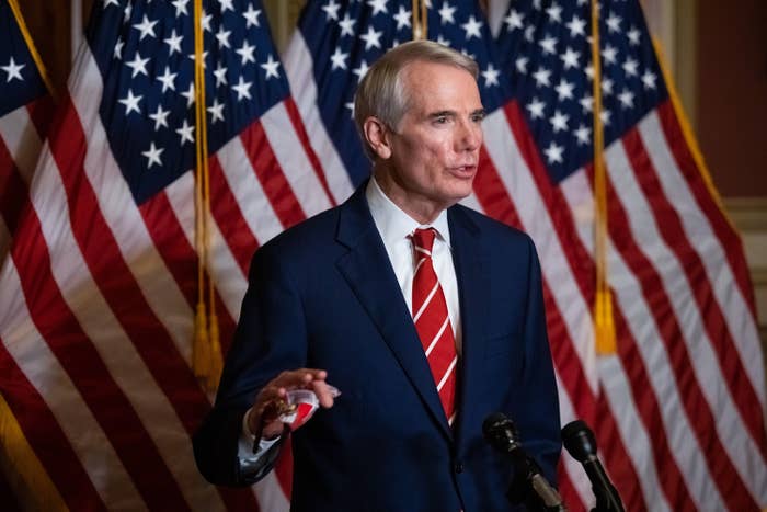 Rob Portman stands in front of some American flags